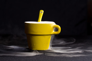 Tazza gialla con cucchiaino con fumo che esce 