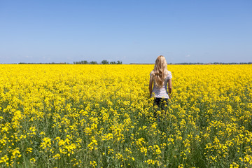 Rapeseed field. Blooming colza field. Beautiful girl in the flowered yellow field. Rapes on the field in summer. Summer concept. agriculture concept. empty space for the text.