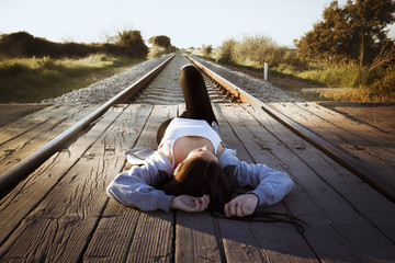 Joven tumbada en las vías del tren mirando a la derecha.