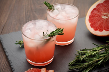 Refreshment grapefruit cocktail with rosemary on slate board.