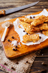 a fish. lunch or dinner, beer snack, fried hake fillets in batter, with spices, black pepper and salt on a wooden board, background