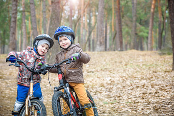 Fototapeta na wymiar Two little siblings having fun on bikes in autumn or spring forest. Selective focus on boy.