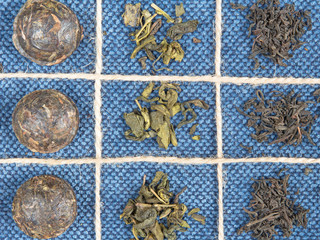Pattern of green leafy black tea laid out in cells on the background of jeans, denim