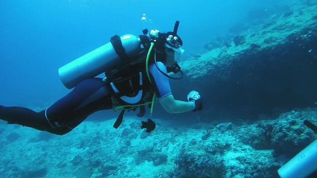 The female scuba diver actively gesticulates and photographs under water, Indian Ocean, Maldives
