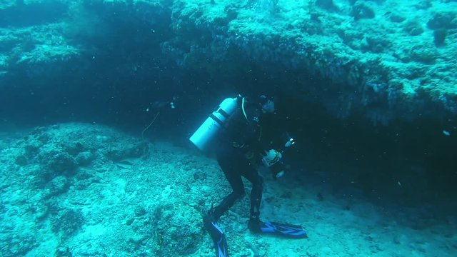 Underwater photographer shooting scool of fish near coral reef, Indian Ocean, Maldives
