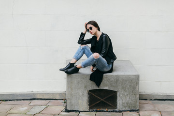 Fashionable model in sunglasses posing at the wall.