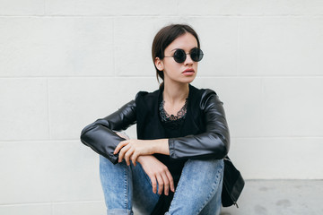 Fashionable model in sunglasses posing at the wall.