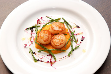 Scallops, creatively arranged food on a white restaurant plate