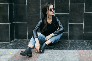 Fashionable model in sunglasses posing at the wall.