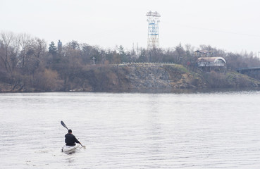 Naklejka premium A man in a white kayak near the city riverbank02