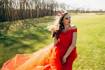 Beautiful woman in a luxurious red dress with a long train