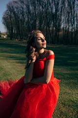 Beautiful woman in a luxurious red dress with a long train