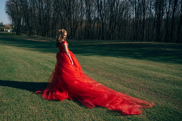 Beautiful woman in a luxurious red dress with a long train