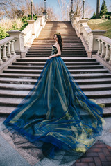 Beautiful woman in a luxurious blue dress with a long train