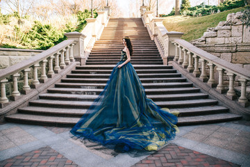 Beautiful woman in a luxurious blue dress with a long train