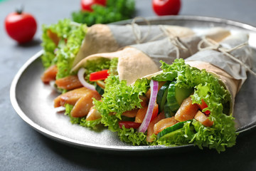 Plate with delicious kebab rolls on grey table
