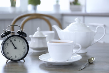 Retro alarm clock showing five minutes to eleven on lunch table
