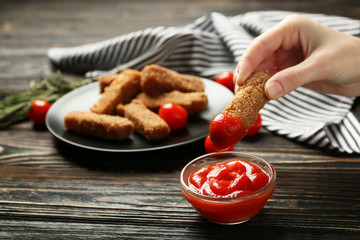 Female hand holding cheese stick with ketchup, closeup