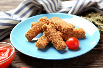 Plate of tasty cheese sticks on wooden background