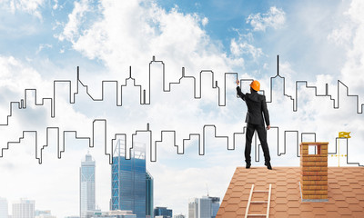 Man architect draw silhouette of modern city on blue sky. Mixed media