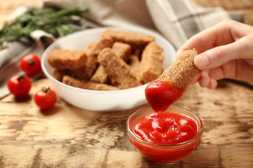 Female hand holding cheese stick with ketchup, closeup