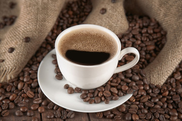 Cup of coffee with roasted beans on  table