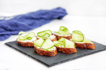 Sandwiches with cheese feta and cucumber on shale board. The concept of food and vegetarianism.