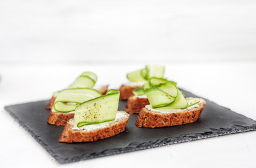 Snacks with cheese feta and cucumber on shale board. The concept of food and vegetarianism.