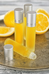 Metal tray with bottles of perfume and lemons on grey wooden background