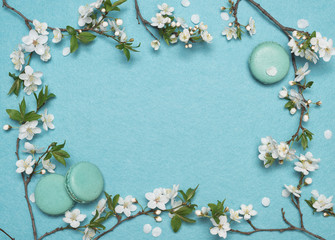 Naklejka na ściany i meble Frame of flowers and French macaroon dessert on a turquoise background