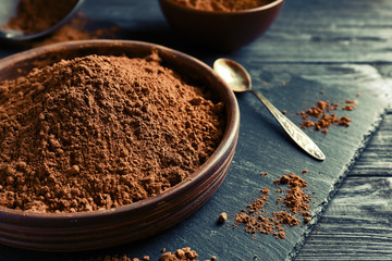 Wooden bowl with cocoa powder on slate plate