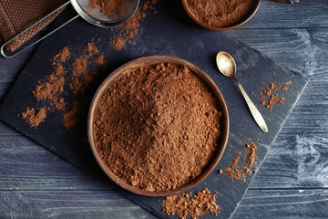 Wooden bowl with cocoa powder on slate plate