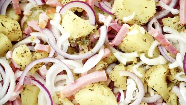 Peeled potatoes with spices, becon meat and onion slices ready to be roasted close up. Food background. Dolly slider shot 4K ProRes HQ codec