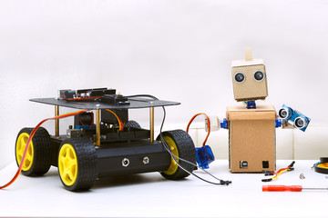 Obraz premium Two robots are on the table, next are the parts for assembling the robot