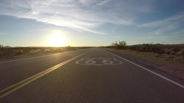 Route 66 pavement sign sunset slow driving shot in the California Mojave Desert.