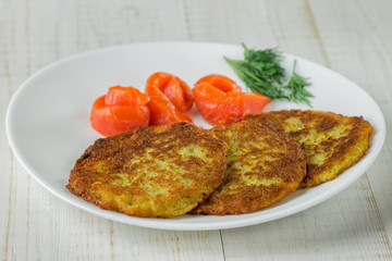 Potato pancakes on a white plate with slices of salmon