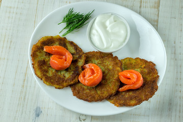 Potato pancakes on a white plate with slices of salmon