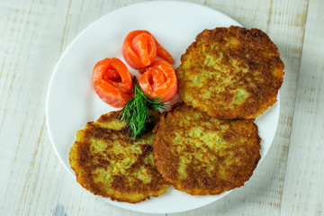 Potato pancakes on a white plate with slices of salmon