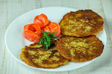 Potato pancakes on a white plate with slices of salmon