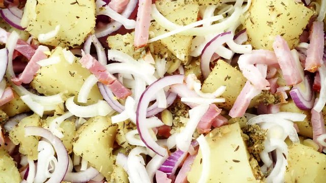 Peeled potatoes with spices, becon meat and onion slices ready to be roasted close up. Food background. Dolly slider shot 4K ProRes HQ codec