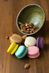 Tasty macaroons and cup of milk with almond on wooden background