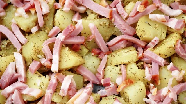 Peeled potatoes with spices, becon meat and onion slices ready to be roasted close up. Food background. Dolly slider shot 4K ProRes HQ codec