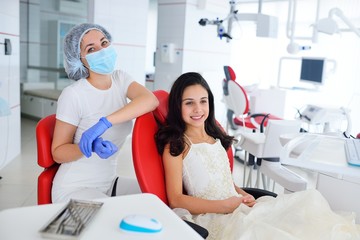 Fototapeta premium Baby girl sitting in red dental chair on examination at dentist