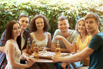 Friends sitting in cafe with fresh beer and tasty pizza