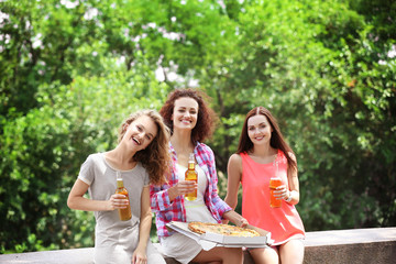 Three female friends with pizza and beer outdoors