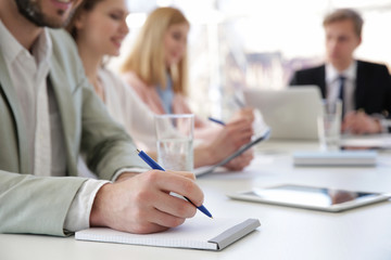 Man making notes in notebook at business presentation