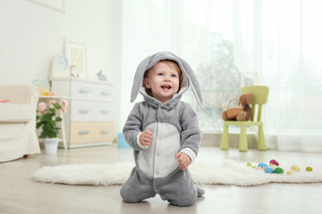 Naklejka premium Cute little baby in bunny costume playing at home