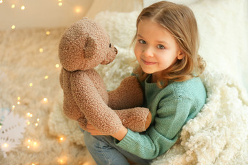 Cute little girl with teddy bear at home