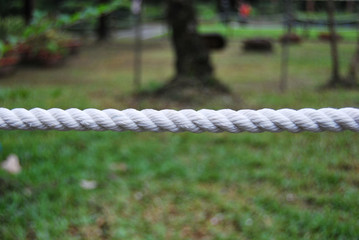 A white cotton rope with blurred garden background. 