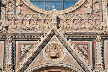 Obraz premium The tympanum of the beautiful marble West facade of the Cathedral Duomo in Siena, Italy